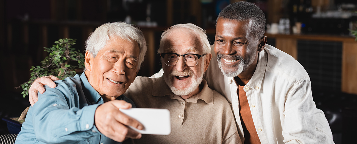 178640635_m smiling asian man taking selfie on smartphone with senior multiethnic friends, banner